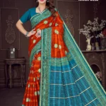 Woman wearing burnt orange and peacock blue Israel Gold saree with green zari border and floral motifs by Sharda Sarees