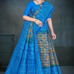 Woman in royal blue Jayraj Checks saree with golden floral body and blue woven pallu featuring peacock motifs by Sharda Sarees